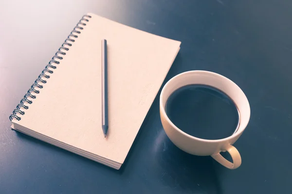 Bok och kaffe cup på svarta träbord — Stockfoto