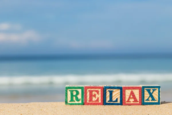 Parola RELAX in blocchi di alfabeto colorato sulla spiaggia tropicale — Foto Stock
