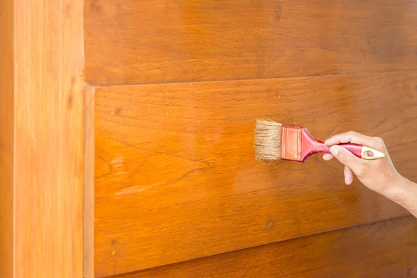 Mano pennello e pittura sulla porta di legno — Foto Stock