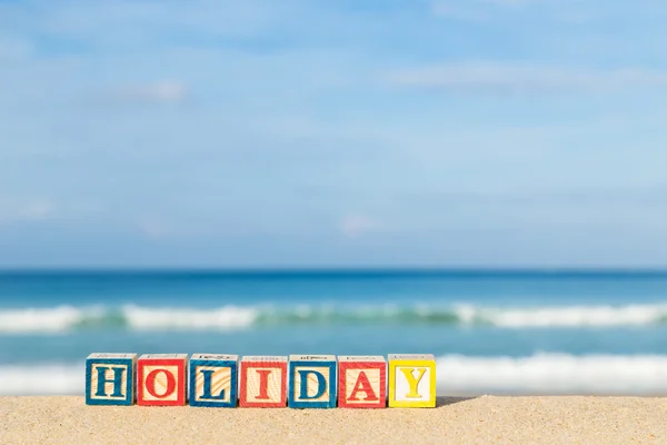 Word HOLIDAY in colorful alphabet blocks on tropical beach — Stock Photo, Image