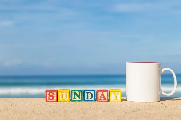 Word SUNDAY in colorful alphabet blocks and coffee cup on tropic — Stock Photo, Image