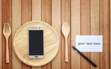 Top view smartphone on wooden dish on wooden plank background