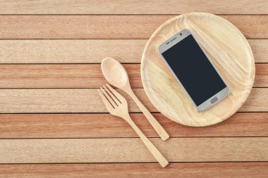 Top view smartphone on wooden dish on wooden plank background
