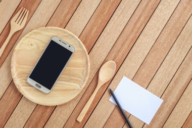 Top view smartphone on wooden dish on wooden plank background
