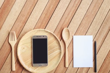 Top view smartphone on wooden dish on wooden plank background
