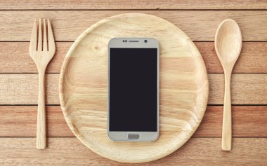 Top view smartphone on wooden dish on wooden plank background