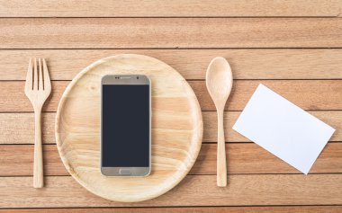 Top view smartphone on wooden dish on wooden plank background