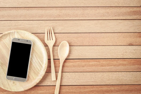 Top view smartphone on wooden dish on wooden plank background