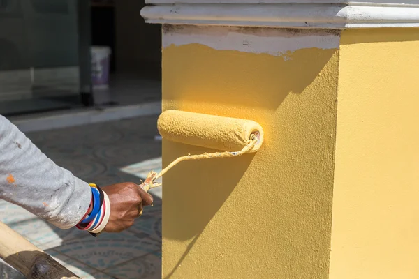 Mano tenendo rullo di vernice e pittura al muro — Foto Stock