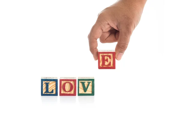 "LOVE "escribir en bloques de alfabeto de madera de colores y la celebración de la mano  " — Foto de Stock