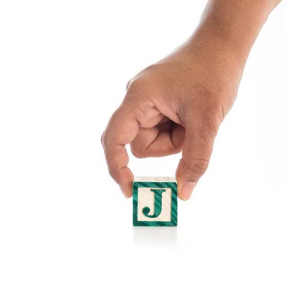 Mano sosteniendo bloques de alfabeto de colores "J" aislado en blanco — Foto de Stock