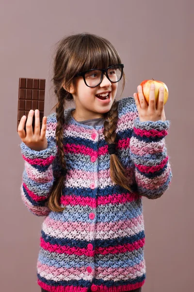 Kleines Nerd-Mädchen mit Apfel und Schokolade — Stockfoto