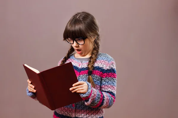 Surprised little nerdy girl with book — Stock Photo, Image