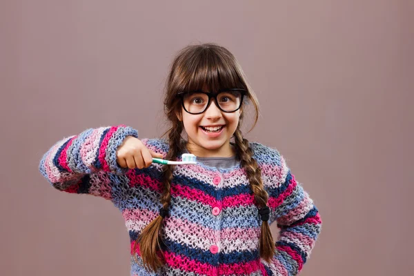 Pequeña chica nerd sosteniendo cepillo de dientes — Foto de Stock