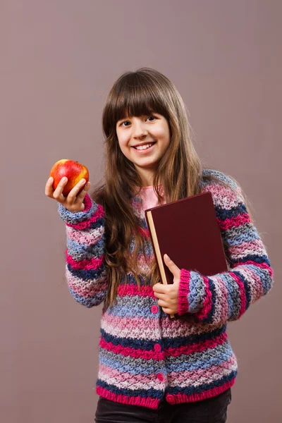 Écolière tenant livre et pomme — Photo