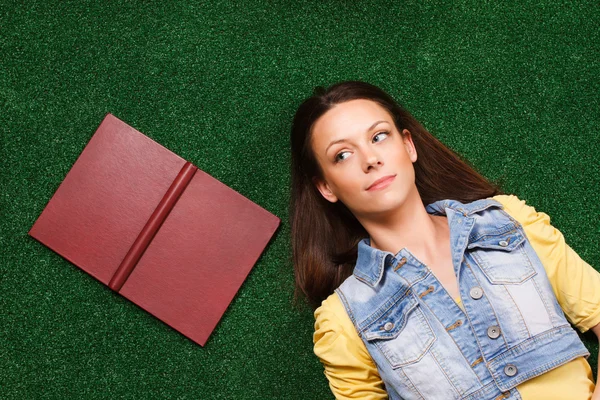 Mujer con libro mintiendo y pensando — Foto de Stock