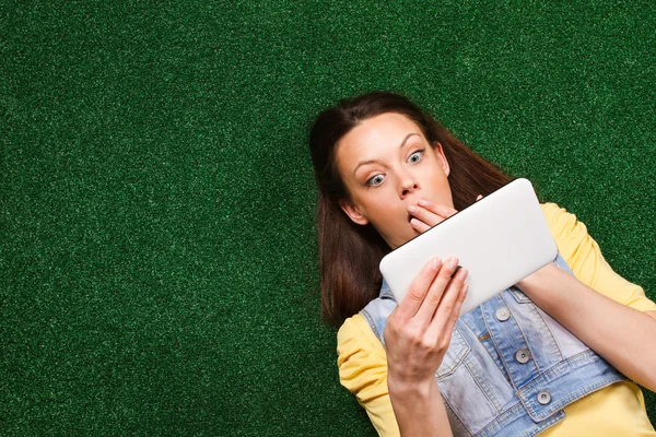 Frau im Gras mit Tablette überrascht — Stockfoto