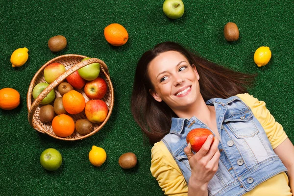 Junge Frau liegt mit Früchten — Stockfoto