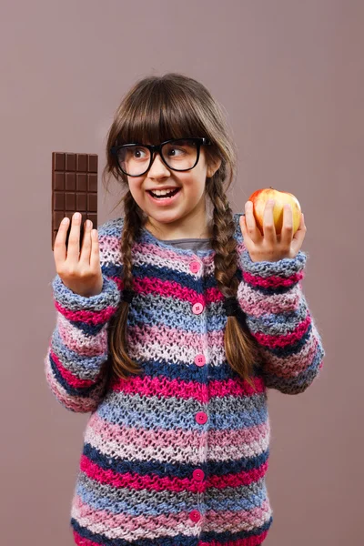 Kleines Nerd-Mädchen mit Apfel und Schokolade — Stockfoto