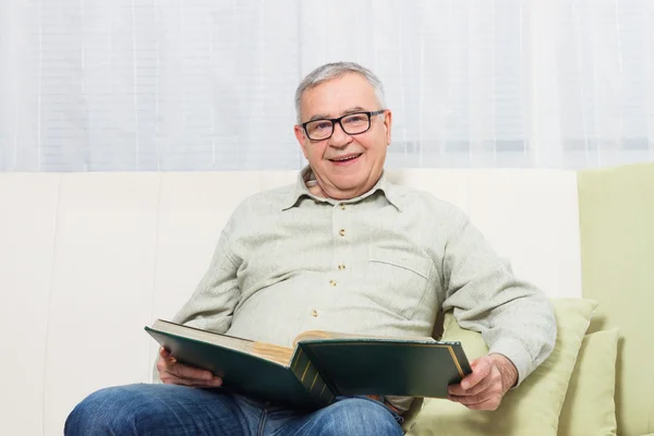 Senior man watching photo album — Stock Photo, Image