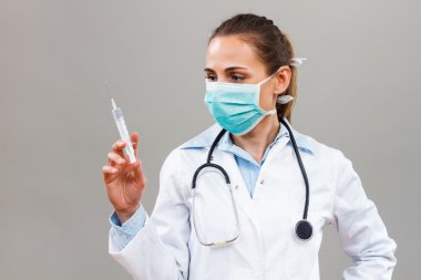 Doktor elinde şırınga tutuyor.