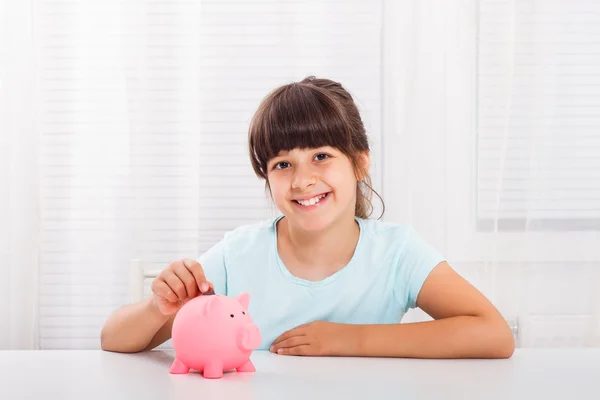 Chica poniendo moneda en alcancía —  Fotos de Stock