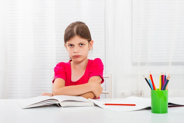 Сердитая школьница за столом — стоковое фото