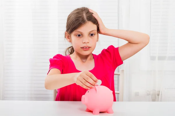 Entrar em pânico menina colocando dinheiro em piggybank — Fotografia de Stock