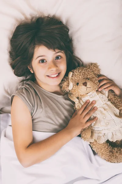 Petite fille au lit avec ours en peluche — Photo