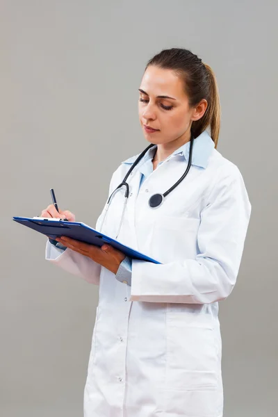 Thinking woman doctor making notes — Stock Photo, Image