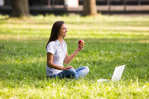 Businesswoman eating apple in park — Stock Photo, Image