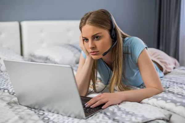 Kulaklıklı Üzgün Kadın Yatak Odasında Dizüstü Bilgisayar Kullanıyor — Stok fotoğraf