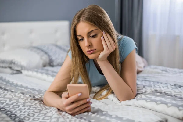 Mujer Triste Sosteniendo Teléfono Mientras Acuesta Cama Dormitorio —  Fotos de Stock