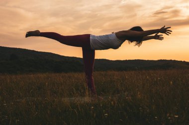 Yoga yapan bir kadının silueti (Virabhadrasana, Savaşçı Pozu).