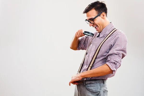 Nerd chico es espiando en su pantalones con lupa —  Fotos de Stock