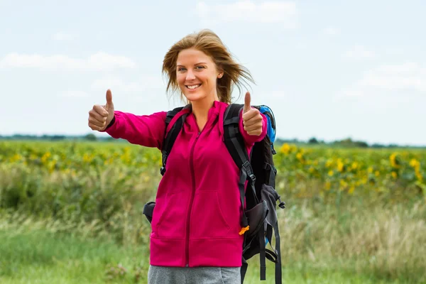 Vrouw met rugzak is klaar om te wandelen en ze is duimen opdagen — Stockfoto