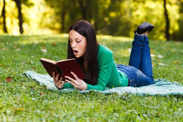 Woman suprised reading a book outdoors — Stock Photo, Image