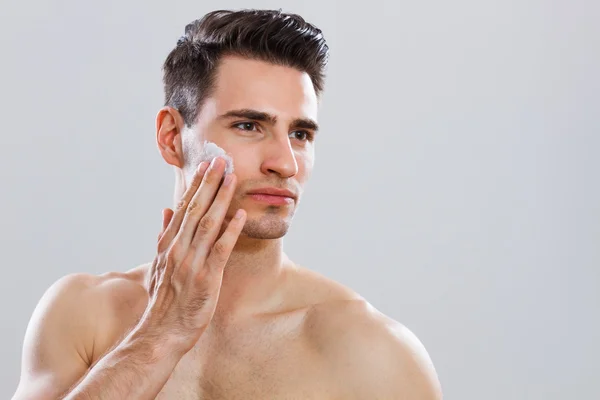 Hombre guapo aplicando crema de afeitar en su cara —  Fotos de Stock