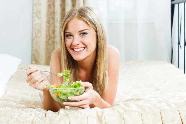 Frau isst Salat im Bett — Stockfoto