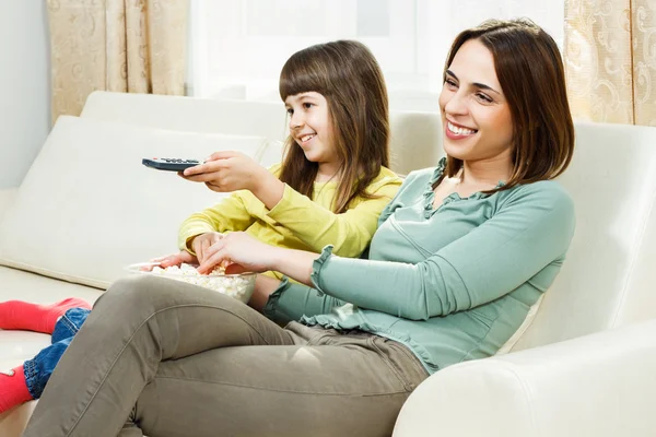 Madre e hija comiendo palomitas de maíz, viendo la televisión — Foto de Stock