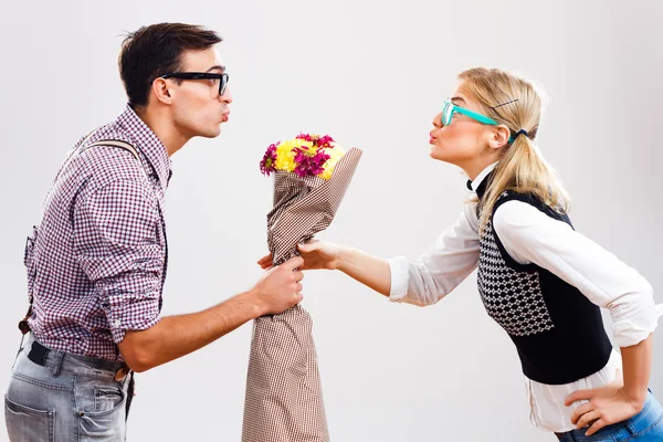 Jovem nerd homem está dando um buquê de flores para sua senhora nerd — Fotografia de Stock