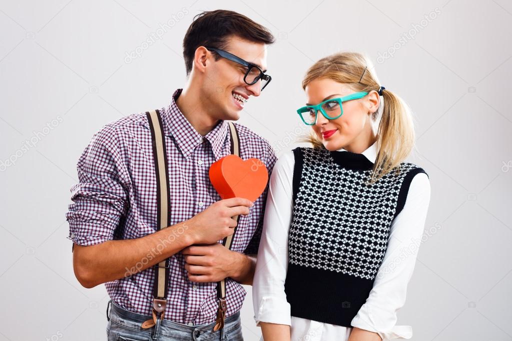 Nerdy man is about to give a red heart to his nerdy lady