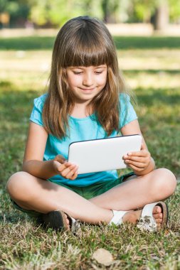 Onun tablet bilgisayar ile parkta oturan kız