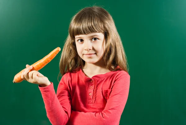 Schattige kleine meisje bedrijf wortel — Stockfoto