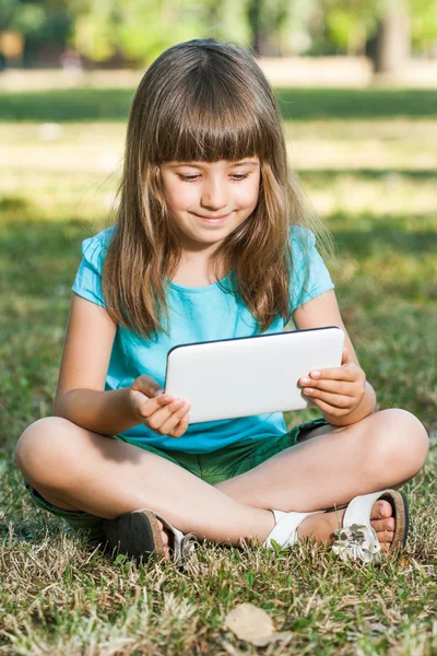 그녀의 태블릿 컴퓨터와 함께 공원에 앉아있는 여자 — 스톡 사진