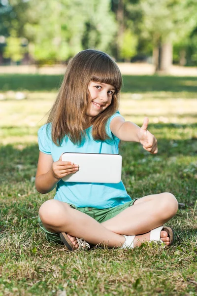 Onun tablet bilgisayar ile parkta oturan kız — Stok fotoğraf