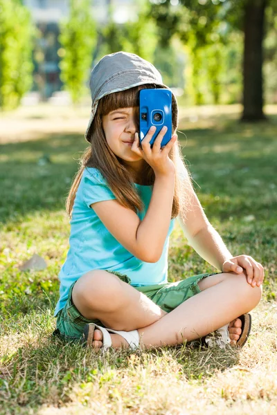 Girl sitting in park and holding photo camera — Stock Photo, Image