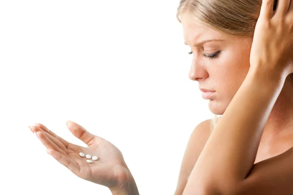 Chica preocupada mirando píldoras en sus manos — Foto de Stock