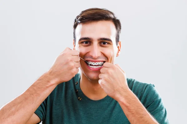 Homme avec appareil dentaire utilisant de la soie dentaire — Photo