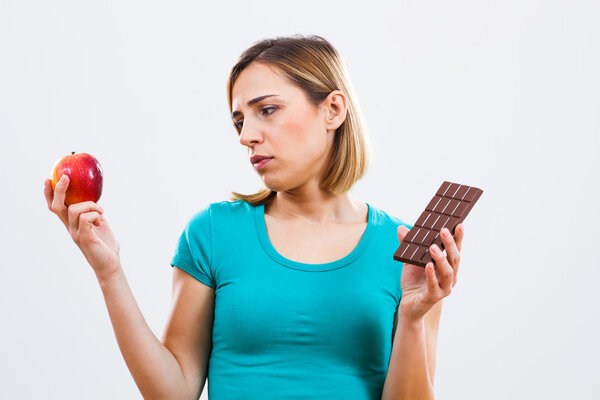 Женщина держит яблоко и шоколад
